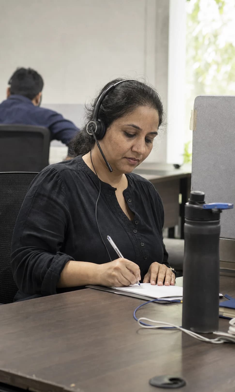 A customer support lead taking notes during a live handoff